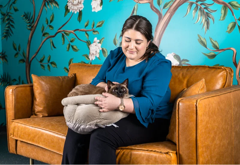 A woman sitting on the sofa while holding her cat